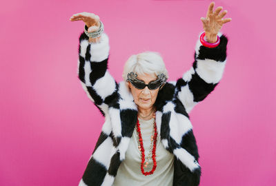 Smiling senior woman gesturing against colored background