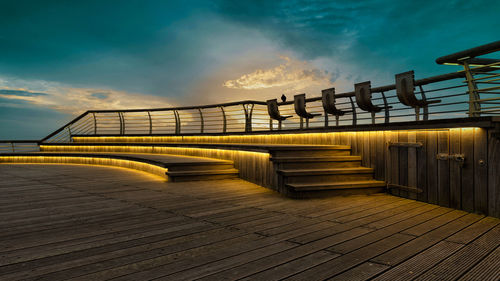 View of bridge on boardwalk against sky during sunset