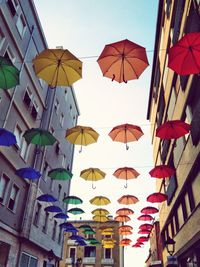 Low angle view of umbrellas against buildings against sky