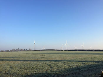 Windmills on field against sky