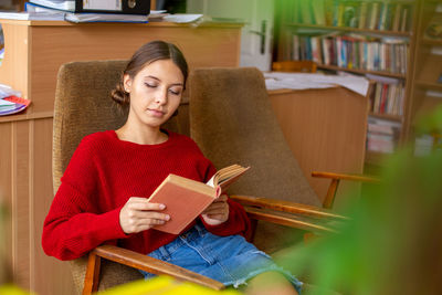 University library beautiful caucasian girl sitting in chair next to bookshelf