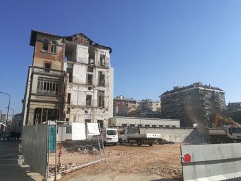 Building by construction site against clear blue sky