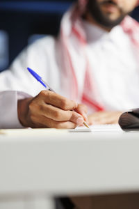 Midsection of woman writing in book