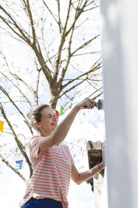 Smiling woman painting fence at yard