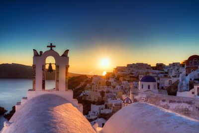 Bell tower against sea during sunset