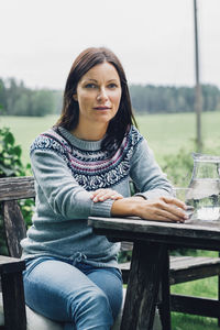 Portrait of confident woman sitting at table in organic farm