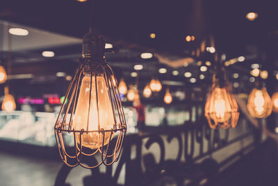 Close-up of illuminated light bulb hanging on ceiling