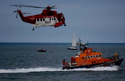 Rescue helicopter and lifeguard boat sailing in sea