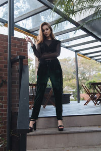 Portrait of young woman standing against railing