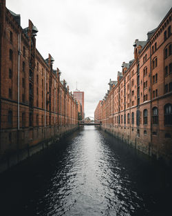 Canal amidst buildings in city against sky