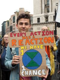 Portrait of young man holding sign in city