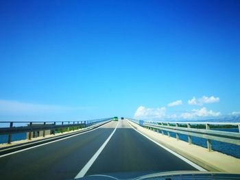 Highway seen through windshield of car against blue sky