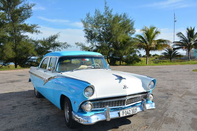 Vintage car on landscape against blue sky