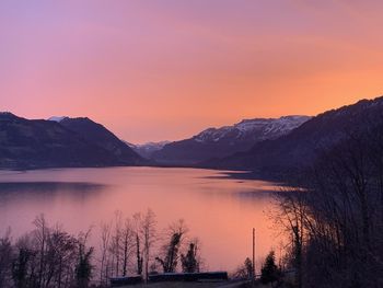 Scenic view of lake by mountains against sky during sunset