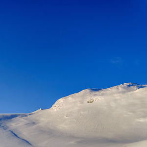 Low angle view of snowcapped mountain against blue sky