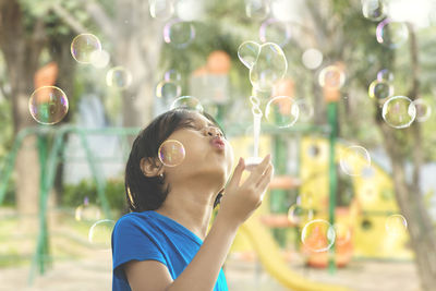 Close-up of cute girl blowing bubbles in mid-air