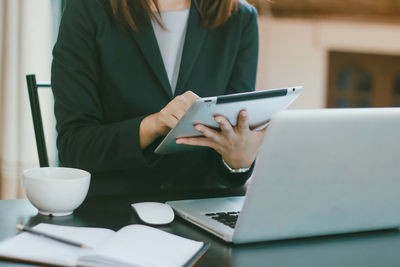 Midsection of woman using laptop on table