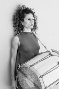 Woman carrying drum standing against wall