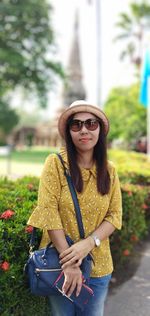 Portrait of smiling young woman wearing sunglasses standing outdoors