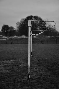 Wooden post on field against sky