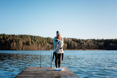 Woman standing wrapped in a towel on a pier after cold water ice swim