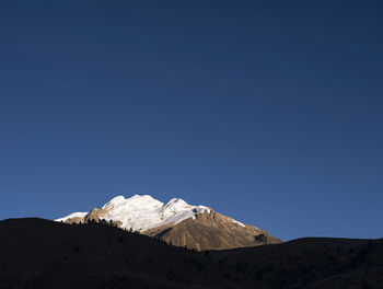 Scenic view of snowcapped mountains against clear blue sky