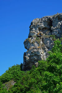 Low angle view of rocky mountains against clear blue sky