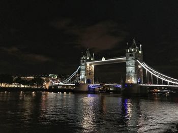 Illuminated suspension bridge over river at night