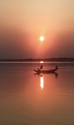Silhouette boats in sea against sky during sunset