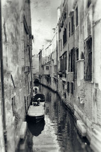 Boats moored in canal amidst buildings in city