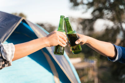 Cropped image of hand holding glass bottle against blurred background