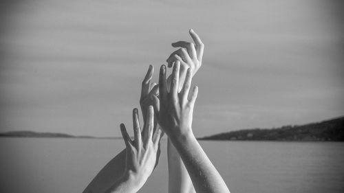 Cropped hands of women gesturing against sea