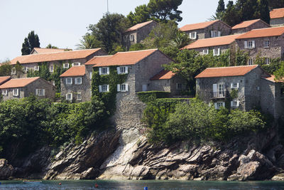 Houses by river against buildings