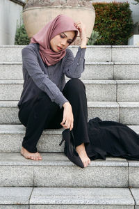 Full length of woman sitting on staircase