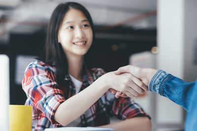 Business people shaking hands over table at office