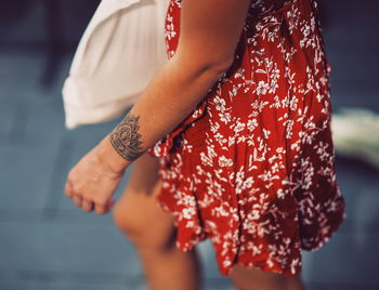 Midsection of woman standing by red leaf