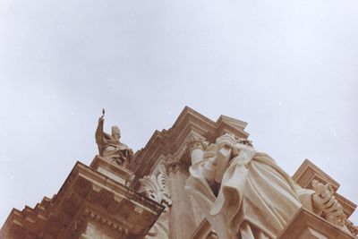 Low angle view of statues on building against sky