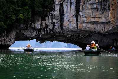 People in boat sailing by rock formation in river