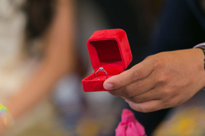 Close-up of bridegroom holding wedding ring in jewelry box