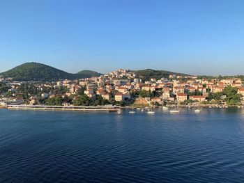 Townscape by sea against clear blue sky