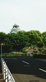 Trees by building against clear sky