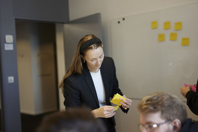 Woman holding post its during business meeting