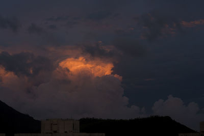 Low angle view of dramatic sky over silhouette buildings