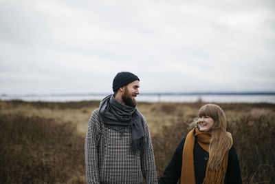 Young couple standing on land against sky