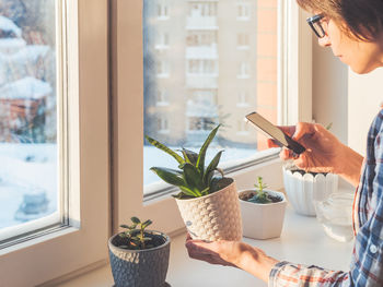 Midsection of woman taking photo of plant