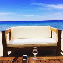 Chairs and table on beach against sky