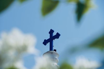  low angle view of cross in sky. church cross with scenic nature frame against blue sky background.