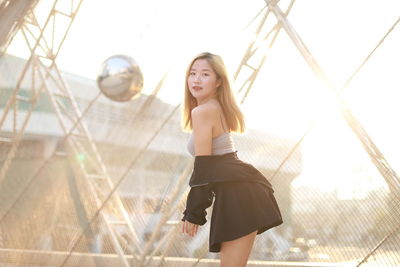 Full length of young woman standing against wall
