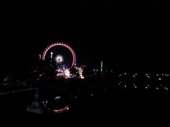 Low angle view of illuminated ferris wheel against sky at night