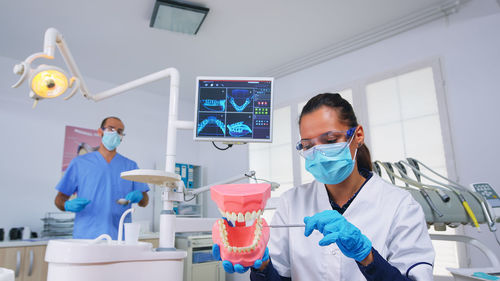 Side view of young woman using mobile phone while standing in laboratory